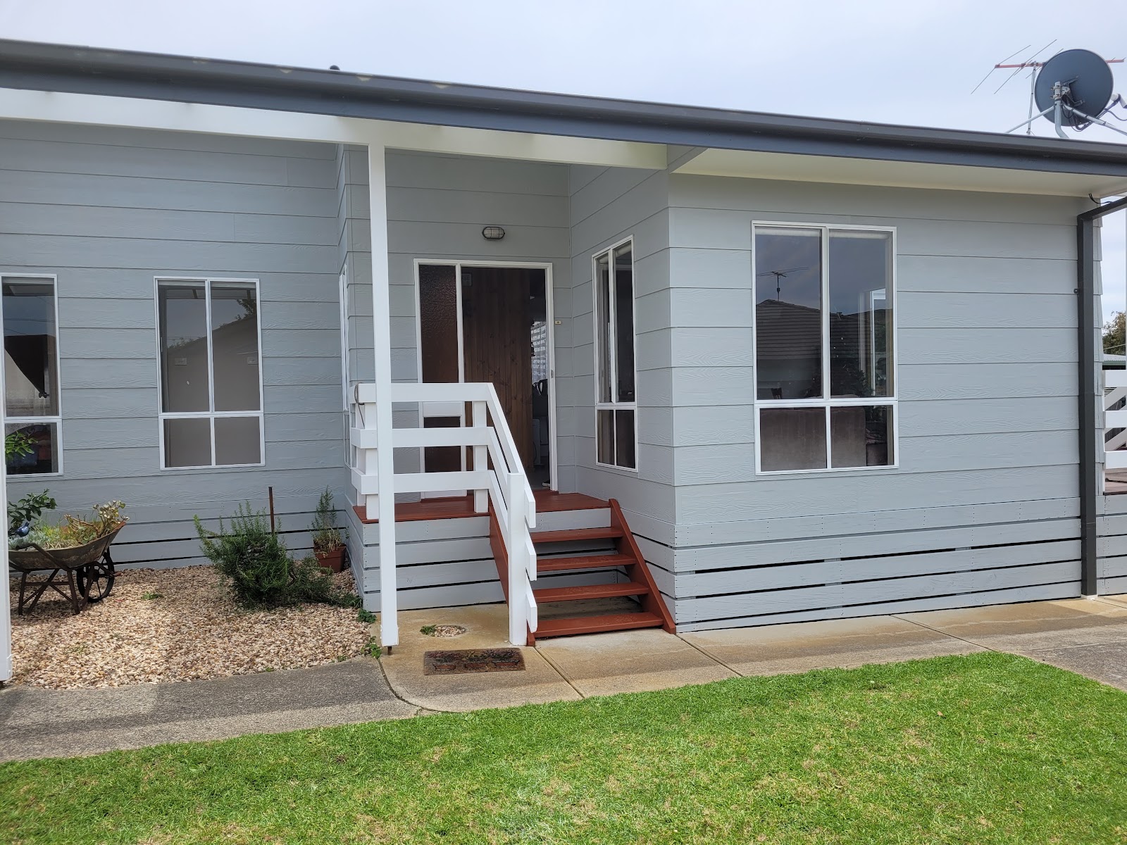 Pale grey weatherboard cottage with fresh white trims and balustrade
